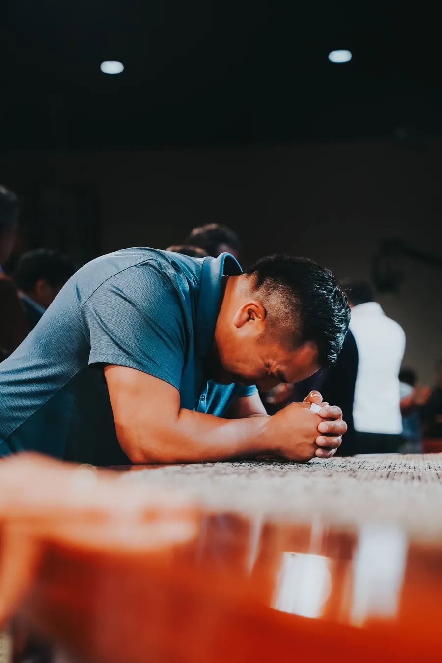 Hombre arrodillado orando con el rostro inclinado sobre el altar