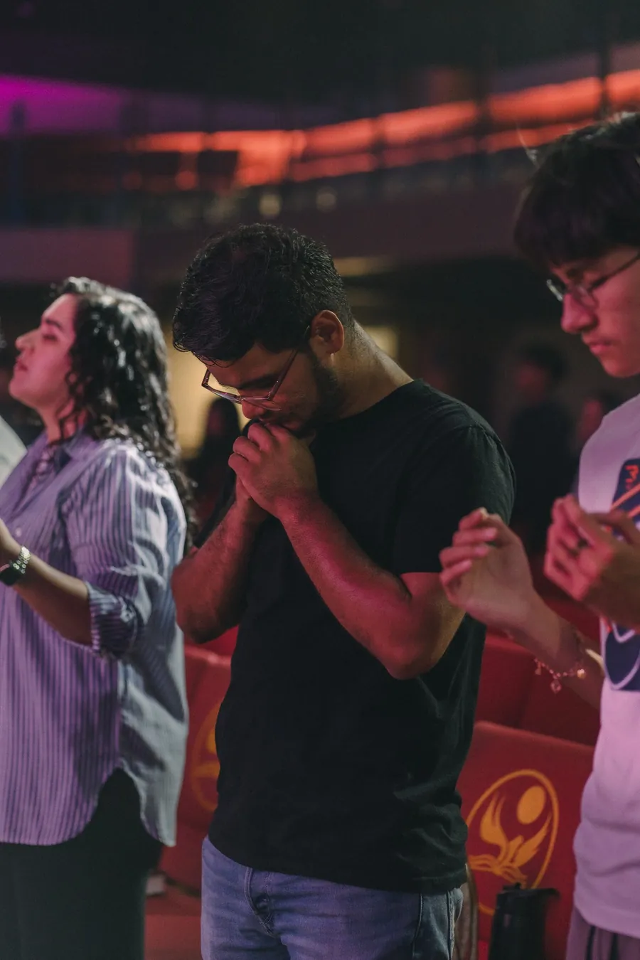 Jóvenes orando con los ojos cerrados durante un servicio