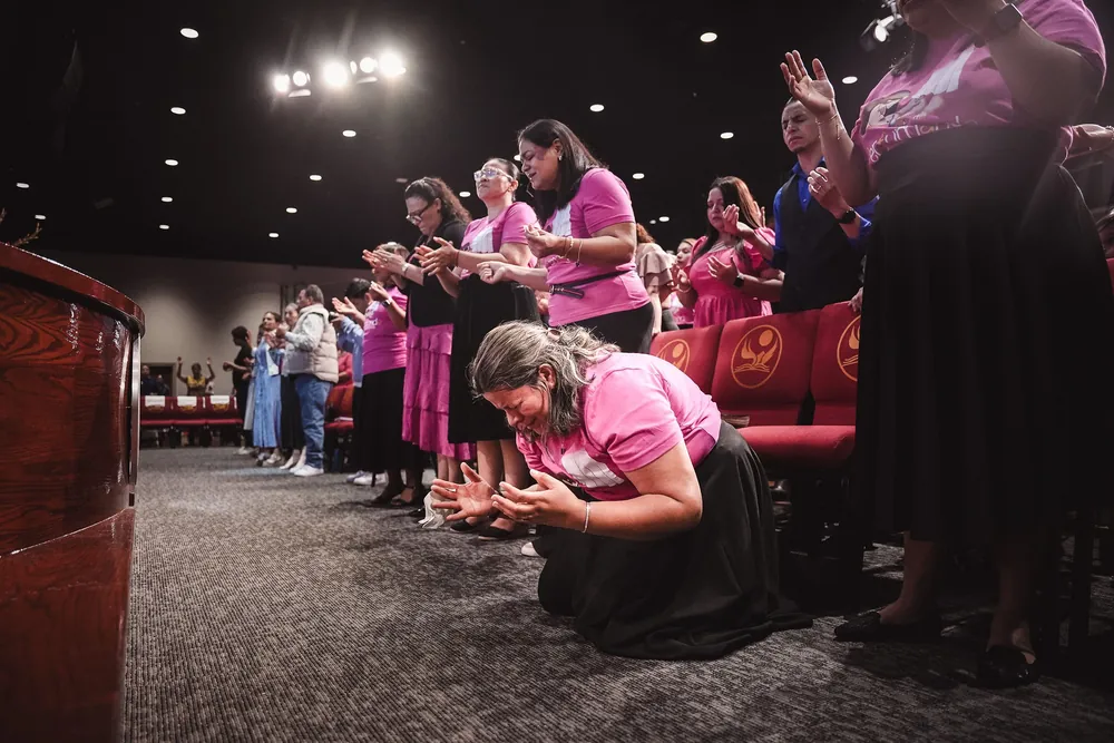 Mujeres de la iglesia orando de rodillas frente al altar
