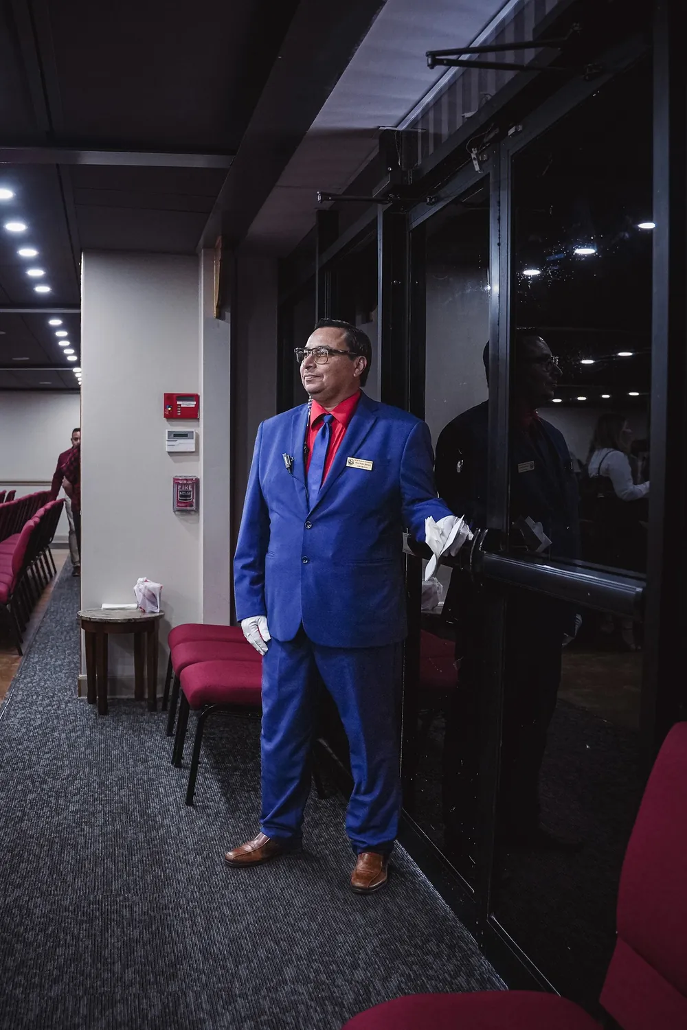 Ujier de traje azul y guantes blancos recibiendo en la entrada del santuario